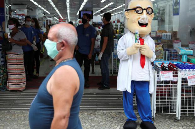 Ricardo Moraes Seorang petugas toko obat, memakai kostum dengan masker pelindung, memperlihatkan semprotan alkohol di sebuah pusat komersial saat penyebaran penyakit virus korona (COVID-19) di Rio de Janeiro, Brazil, Kamis (16/4/2020).