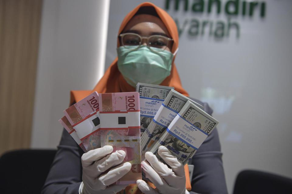 Karyawan menunjukkan uang rupiah dan dolar AS di Bank Mandiri Syariah, Jakarta, Senin (20/4/2020). Nilai tukar rupiah terhadap dolar Amerika Serikat (AS) menguat pada penutupan perdagangan Senin (20/4) sebesar 52 poin atau 0,34 persen ke level Rp15.412 pe