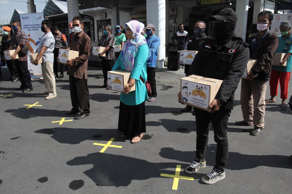 Warga berdiri dengan menjaga jarak saat menerima paket sembako di halaman Stasiun Yogyakarta, DI Yogyakarta, Kamis (30/4/2020). PT Kereta Api Indonesia Daop 6 membagikan 700 paket sembako kepada masyarakat di lingkungkan stasiun, karyawan, tukang becak da