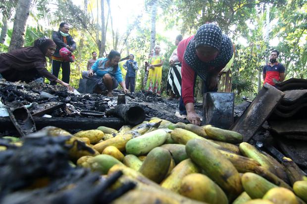 Warga memilah barang yang masih bisa diselamatkan dari puing-puing rumah yang terbakar di Pondok Nongko, Banyuwangi, Sabtu (2/5/2020). Rumah yang berada tengah kebun kelapa dan jauh dari pemukiman warga itu, terbakar pada jumat (01/05) akibat lampu teplok