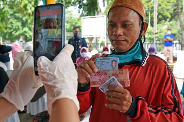 Warga penerima manfaat bantuan sosial tunai difoto petugas di Kantor Pos Serang, Banten, Rabu (6/5/2020). Bansos berupa uang tunai Rp600 ribu per KK per bulan diberikan kepada keluarga miskin dan rentan miskin dampak pandemi COVID-19 selama tiga bulan ke 