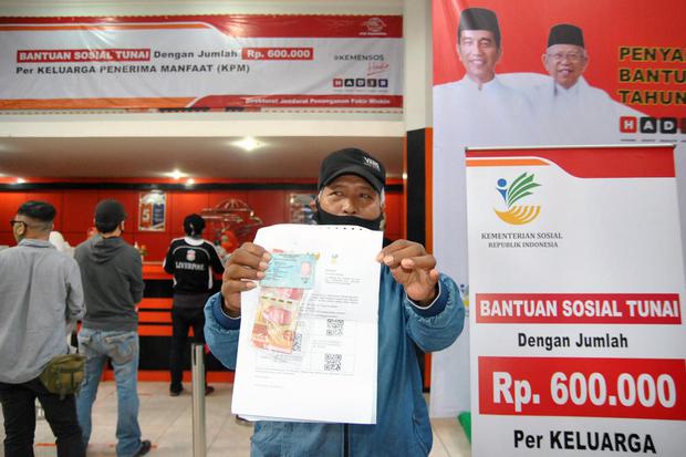 Warga menunjukkan uang tunai saat penyerahan Bantuan Sosial Tunai (BST) di Kantor Pos Bogor, Jawa Barat, Rabu (13/5/2020). BST diberikan kepada Keluarga Penerima Manfaat (KPM) yang terdampak pandemi virus Corona (COVID-19) yang disalurkan melalui PT Pos I