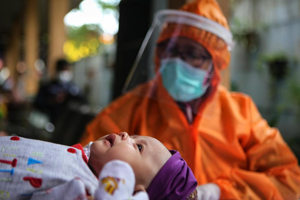 Petugas menggunakan alat pelindung diri (APD) menimbang berat badan bayi saat imunisasi di Puskesmas Karawaci Baru, Kota Tangerang, Banten, Rabu (13/5/2020). 