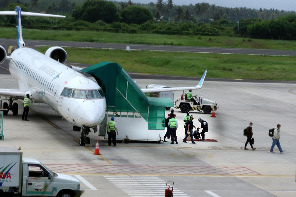 Penumpang keluar dari pesawat di Bandara Banyuwangi, Jawa Timur, Sabtu (16/5/2020). Setelah aktivitas penerbangan ditutup untuk menghindari penyebaran wabah COVID-19, mulai hari ini penerbangan kembali dibuka dengan menerapkan protokol pencegahan penular