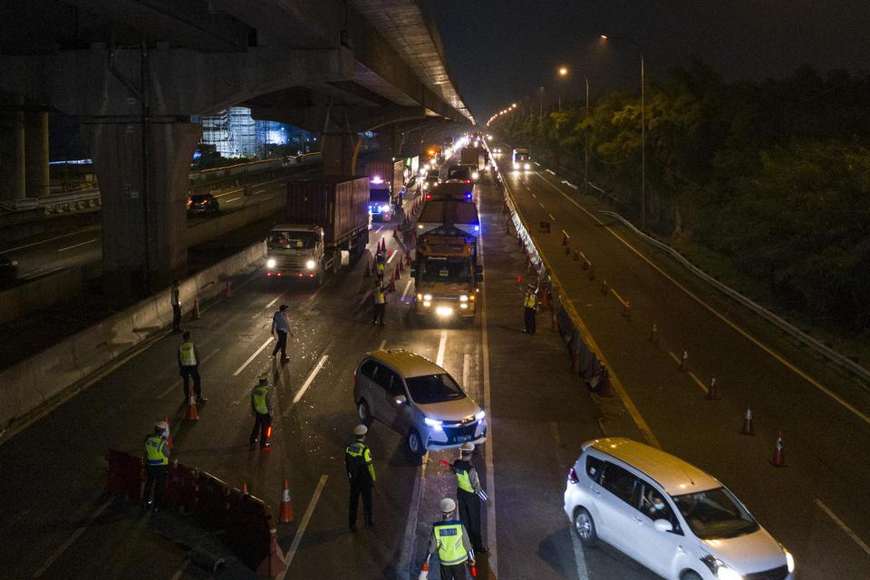 Petugas kepolisian mengarahkan kendaraan pribadi yang melintas di tol Jakarta-Cikampek. Jumlah kendaraan yang keluar dari Jakarta hingga 22 Mei 2020 tercatat sebanyak 430.993 kendaraan.