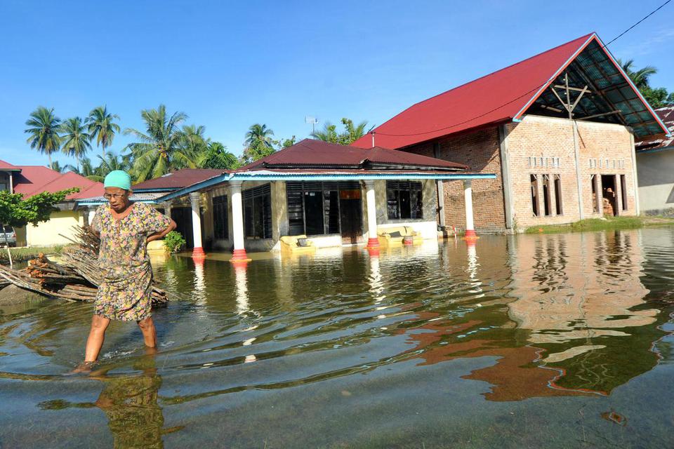 Warga berjalan di depan rumahnya yang terendam banjir rob di Tiram Ulakan, Kabupaten Padangpariaman, Sumatera Barat, Senin (25/5/2020). Banjir rob akibat pasang air laut itu menggenangi kawasan tersebut sejak dua hari terakhir, mengakibatkan sejumlah ruma