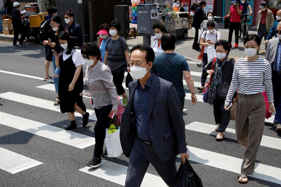Kim Hong-Ji Pejalan kaki memakai masker pelindung menyebrangi sebuah jalan, di tengah penyebaran penyakit virus korona (COVID-19) di Seoul, Korea Selatan, Kamis (28/5/2020).