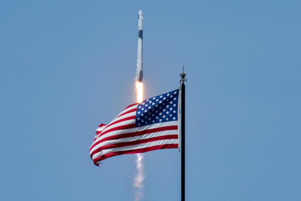 Bendera Amerika Serikat terlihat saat roket SpaceX Falcon 9 dan pesawat luar angkasa Crew Dragon membawa astronot NASA Douglas Hurley dan Robert Behnken meluncur dalam misi SpaceX Demo-2 NASA ke Stasiun Luar Angkasa Internasional dari Kennedy Space Center