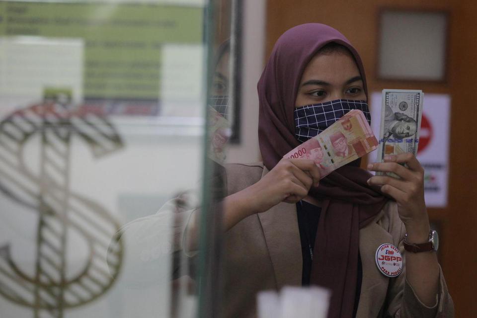Karyawati menunjukkan mata uang rupiah dan dolar AS di salah satu gerai penukaran mata uang asing di Jakarta, Minggu (7/6/2020). Nilai tukar rupiah diperkirakan bakal melanjutkan tren penguatan di pekan kedua di Juni 2020 dimana pada penutupan Jumat (5/6)