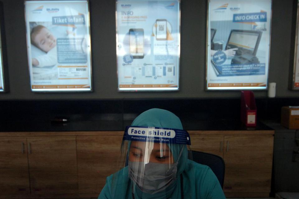 Petugas menggunakan penutup wajah duduk di tempat pembelian tiket saat persiapan pengoperasian KA Kaligung di Stasiun Tegal, Jawa Tengah, Kamis (11/6/2020). Menurut PT KAI Daop 4 Semarang ditengah pandemi COVID-19 dengan tetap menerapkan protokol kesehata