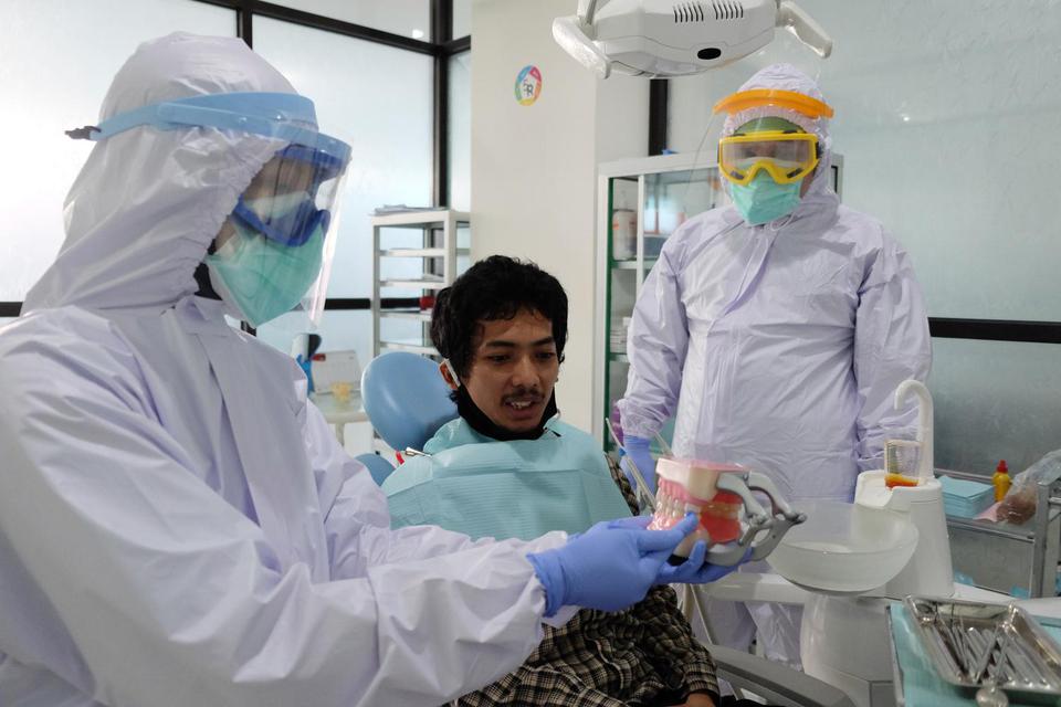 Dokter memakai alat pelindung diri (APD) level III (tiga) saat memeriksa kesehatan gigi pasien di Rumah Sakit Gigi dan Mulut Soelastri, Solo, Jawa Tengah, Kamis (11/6/2020). Rumah sakit setempat menerapkan pedoman pelayanan selama pandemi COVID-19 bagi do