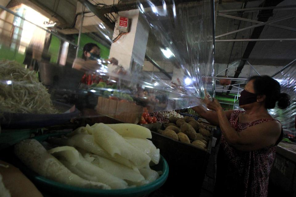 Warga membeli bahan pangan di Pasar Genteng Baru, Surabaya, Jawa Timur, Minggu (14/6/2020). Pemerintah Kota Surabaya menerapkan protokol kesehatan di pasar tersebut dengan memasang penyekat plastik di lapak pedagang, pemberlakuan sirkulasi pengunjung deng