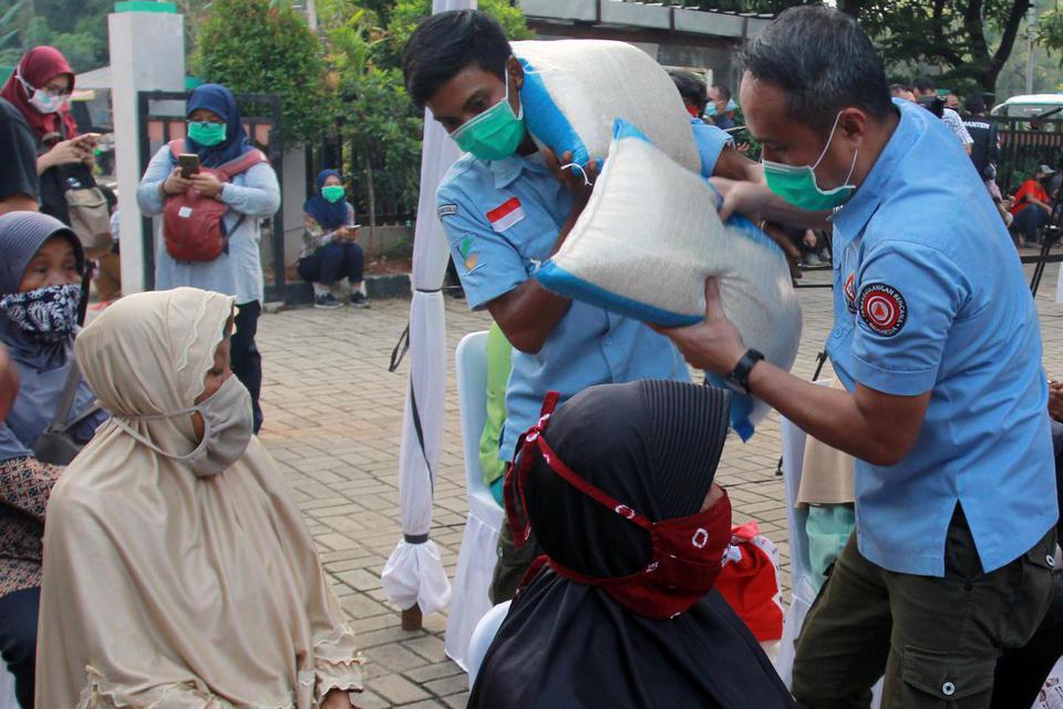 Petugas Kemensos memberikan beras kepada warga penerima paket sembako bantuan pemerintah tahap lima kepada warga di Rawa Buntu, Tangerang Selatan, Banten, Selasa (23/6/2020). Sebanyak 1.164 paket sembako diberikan kepada keluarga miskin, tidak mampu dan r