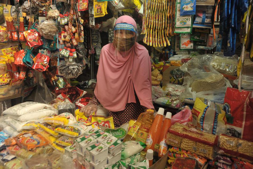Seorang pedagang memakai pelindung (face shield) di wajahnya usai sosialisasi alat pelindung diri (APD) bagi pedagang di Pasar Sekip Ujung, Palembang, Sumatera Selatan, Jumat (26/6/2020). Sosialisasi APD tersebut dilakukan agar pedagang pasar memahami pen