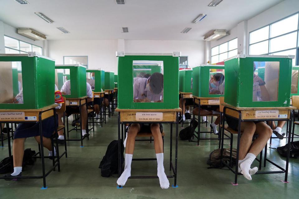 Athit Perawongmetha Siswa sekolah Sam Khok memakai masker dan pelindung wajah terlihat di dalam kotak suara yang difungsikan kembali sebagai partisi dalam kelas saat kegiatan belajar i kembali dimulai di seluruh negeri setelah pemerintah melonggark