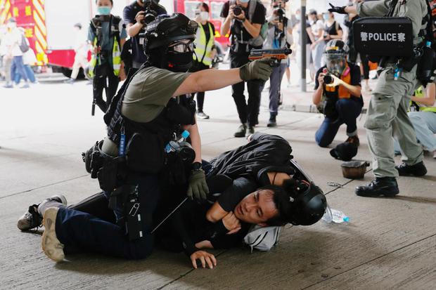 Tyrone Siu Seorang polisi mengangkat senjata semprotan merica saat ia menahan seorang pria saat demonstrasi atas undang-undang keamanan nasional dalam peringati penyerahan Hong Kong ke China dari Britain di Hong Kong, China, Rabu (1/7/2020).