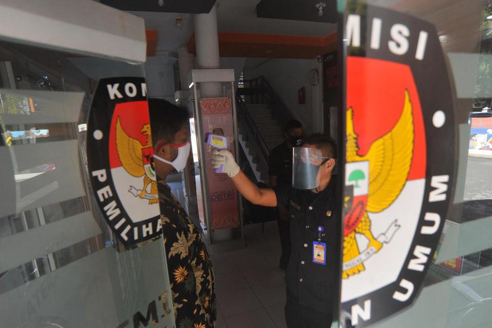 Petugas menggunakan pelindung wajah mengecek suhu tubuh staf yang datang di Kantor Komisi Pemilihan Umum (KPU) Sumatera Barat, di Padang, Jumat (10/7/2020). KPU pusat menyiapkan perlengkapan APD dan fasilitas kesehatan untuk panitia dan peserta pemilu di 