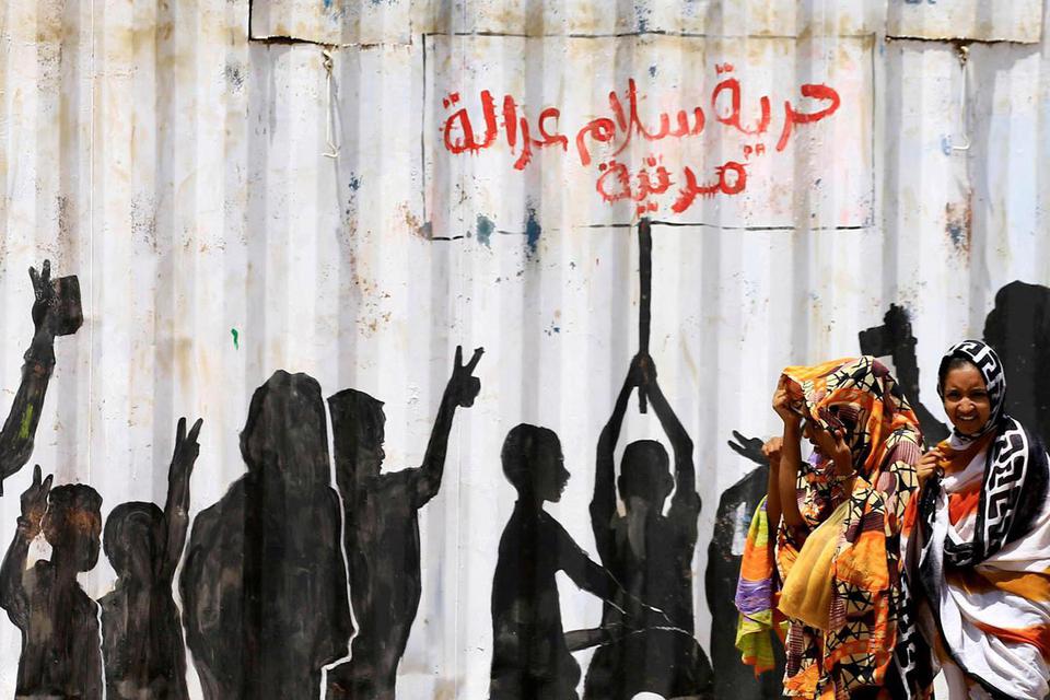 Mohamed Nureldin Abdallah/File Photo ARSIP FOTO: Warga sipil berjalan melewati tulisan grafiti dalam bahasa Arab "Freedom, Peace, Justice and Civilian" (kebebasan, kedamaian, keadilan dan sipil) di distrik Burri di Khartoum, Sudan, Jumat (10/7/2020).