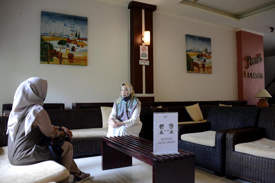 Petugas hotel (kanan) mengenakan alat pelindung wajah (Face shield) dan masker berbincang dengan seorang tamu di Hotel Oasis, Banda Aceh, Aceh, Rabu (15/7/2020). Untuk membangkitkan kembali sektor pariwisata dan ekonomi kreatif yang terdampak pandemi COVI