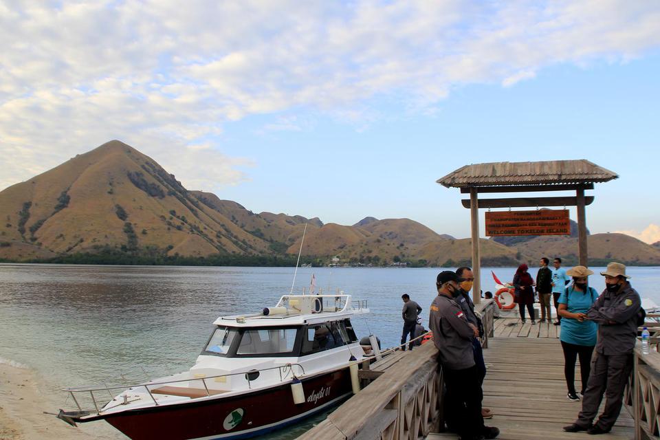 Petugas taman nasional menggunakan masker saat bertugas di pintu masuk kawasan wisata Pulau Kelor di Taman Nasional (TN) Komodo, Manggarai Barat, NTT, Sabtu (18/7/2020). Balai Taman Nasional Komodo telah membuka kembali kawasan wisata di TN Komodo secara 