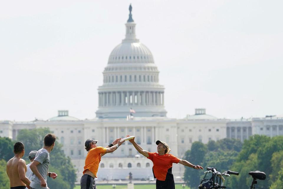 Kevin Lamarque Dua pemain berusaha mendapatkan frisbee dalam permainan di National Mall dengan latar belakang gedung Capitol saat terjadi gelombang panas di Washington, Amerika Serikat, Senin (20/7/2020).