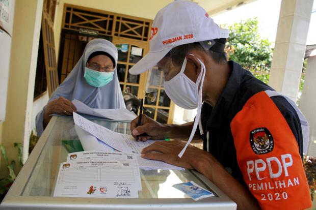 Petugas Pemutakhiran Data Pemilih (PPDP) melakukan pencocokan dan penelitian (coklit) data pemilih Pilkada Serentak 2020 di salah satu rumah warga di Makassar, Sulawesi Selatan, Rabu (22/7/2020). Para PPDP setempat diwajibkan menerapkan protokol kesehatan