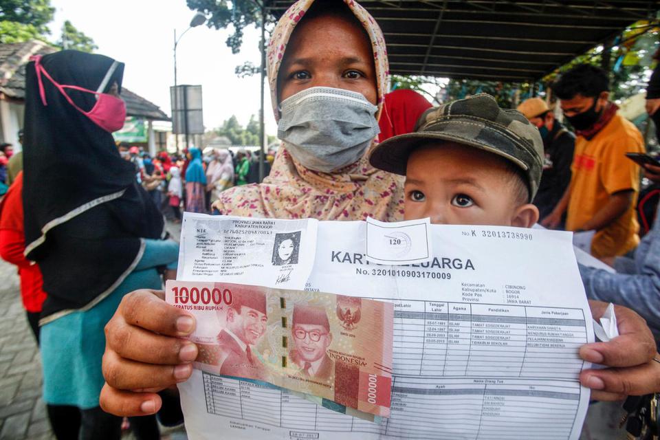 Warga menerima bantuan sosial (Bansos) tahap dua Provinsi Jawa Barat, di Kelurahan Harapan Jaya, Cibinong, Bogor, Jawa Barat, Kamis (23/7/2020). Pemerintah Provinsi Jawa Barat menyatakan penyaluran  bansos tahap dua ini menyasar 1.392.407 Keluarga Rumah 