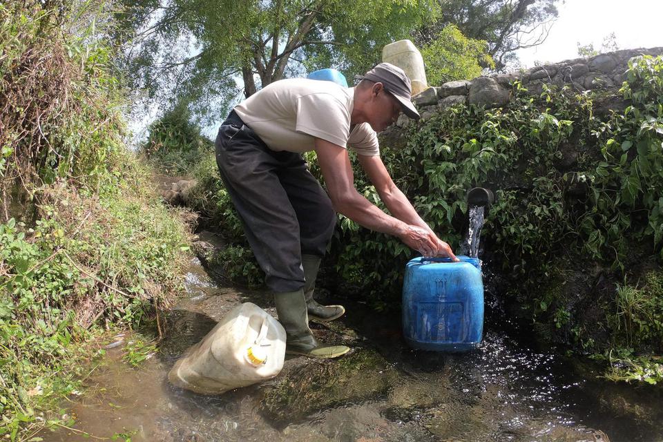 Seorang warga Sungai Jambu menampung air yang mengalir dari sumber mata air di kaki Gunung Kerinci, Kayu Aro Barat, Kerinci, Jambi, Minggu (2/8/2020). Beberapa desa yang wilayahnya belum mendapatkan layanan Perusahaan Daerah Air Minum (PDAM) di daerah itu