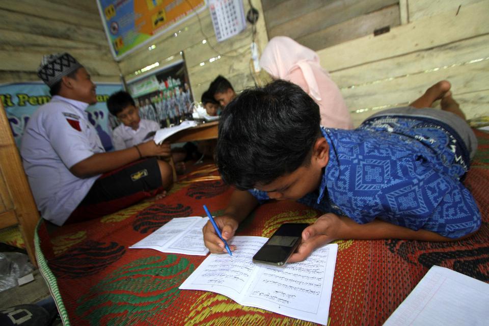 Sejumlah siswa mengikuti proses belajar mengajar dalam jaringan (daring) di bekas posko COVID-19 di tepi jalan untuk mendapatkan sinyal jaringan internet, di Desa Madang, Kabupaten Hulu Sungai Selatan, Kalimantan Selatan, Selasa (4/8/2020). 