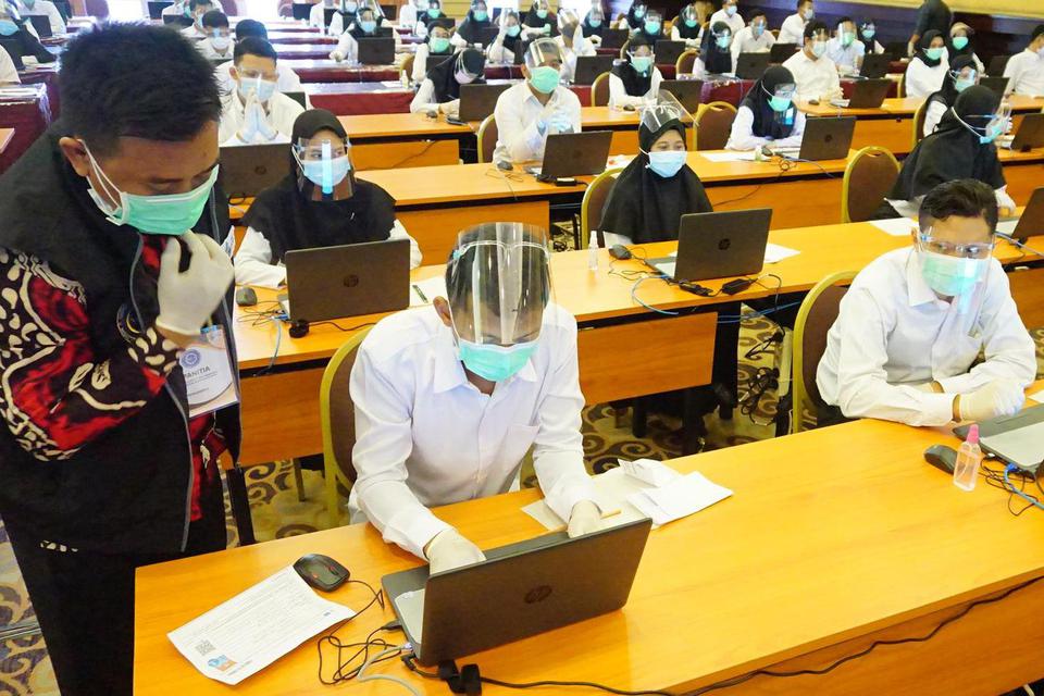 Petugas memandu peserta melakukan proses login komputer ujian Seleksi Kemampuan Bidang (SKB) di program penjaringan CPNS 2019 di Tulungagung, Jawa Timur, Rabu (30/9/2020). Ujian seleksi CPNS 2019 yang diikuti 1.505 peserta itu digelar dengan menerapkan pr