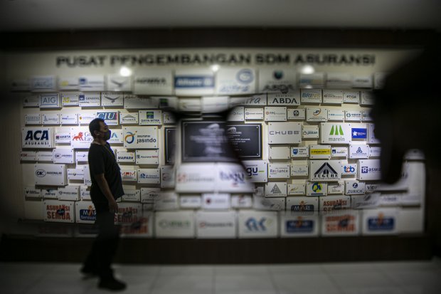 Karyawan melintasi logo-logo perusahaan asuransi di Kantor Asosiasi Asuransi Umum Indonesia (AAUI), Jakarta, Rabu (30/9/2020). Direktur Eksekutif Asosiasi Asuransi Umum Indonesia (AAUI) Dody Achmad Sudiyar Dalimunthe menjelaskan bahwa kemungkinan industri