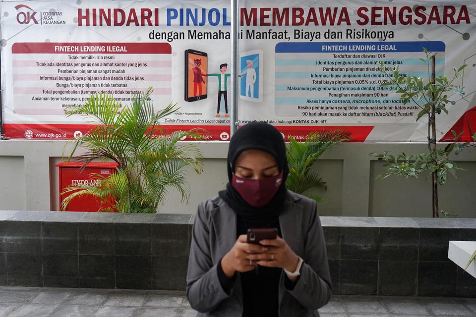 Warga berada di dekat poster edukasi waspada fintech ilegal di kantor Otoritas Jasa Keuangan (OJK) Yogyakarta, Rabu (4/11/2020). Satgas Waspada Investasi (SWI) yang beranggotakan 13 kementerian dan lembaga pada Oktober ini menemukan dan memblokir 206 fint