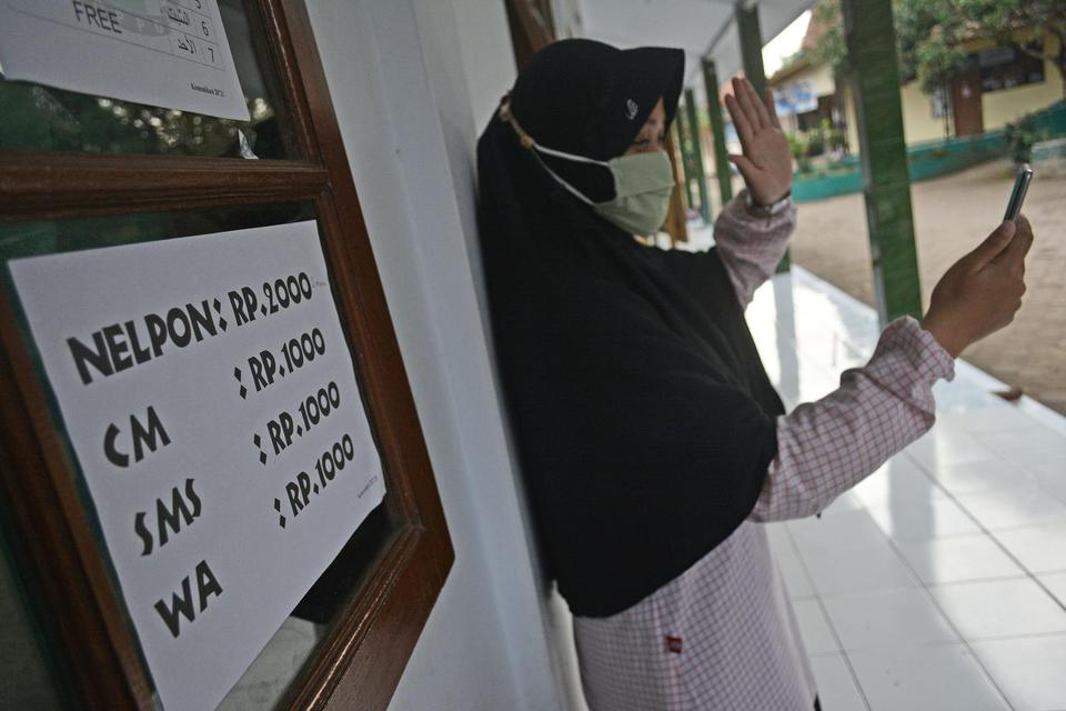 Seorang santri putri berkomunikasi dengan orang tua melalui telepon genggam di Pondok Pesantren Darussalam, Kersamanah, Kabupaten Garut, Jawa Barat, Senin (9/11/2020). Selain menerapkan 3M, pondok pesantren tersebut juga memperketat protokol kesehatan sep