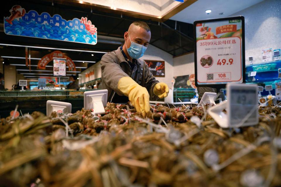 Thomas Peter Seorang staf meletakkan makanan laut di sebuah supermarket menyusul penyebaran penyakit virus korona (COVID-19) di Beijing, China, Rabu (11/11/2020). Foto diambil tanggal 11 November 2020.