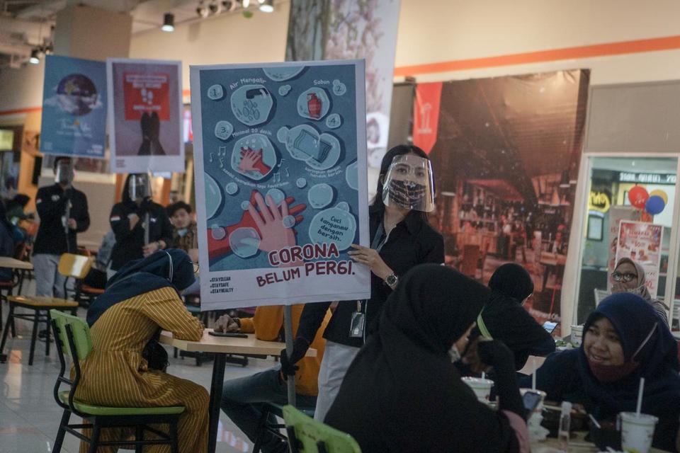 Karyawan pusat perbelanjaan berkeliling dengan membawa poster saat aksi sosialisasi bahaya COVID-19, di Grand Mall, Solo, Jawa Tengah, Senin (7/12/2020). Aksi tersebut untuk mengingatkan pengunjung pentingnya meningkatkan kewasapaan terhadap COVID-19 deng