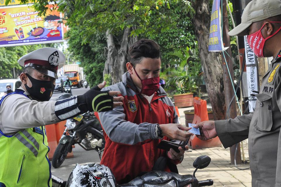 Petugas gabungan dari Kepolisian dan Satpol PP memberhentikan pengendara motor yang tidak menggunakan masker dan memeriksa identitas, di Ujung Menteng, Jakarta Timur, Jumat (18/12/2020). Penyekatan di perbatasan tersebut dilakukan untuk mencegah penularan