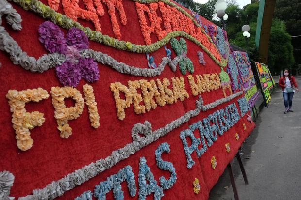 Warga melintas di depan karangan bunga dukungan atas pembubaran organisasi Front Pembela Islam (FPI) di dekat kawasan gedung DPRD Medan, Sumatera Utara, Kamis (31/12/2020). Puluhan karangan bunga dari berbagai elemen masyarakat di kota tersebut berisi duk