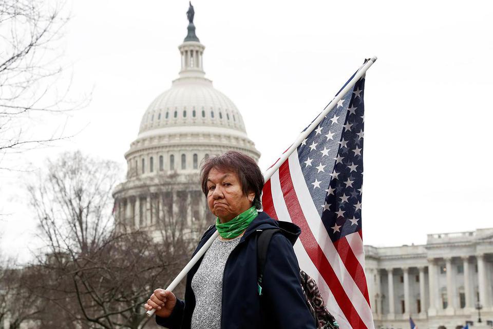 Shannon Stapleton Seorang pendukung Presiden AS Donald Trump membawa bendera AS dalam aksi protes di gedung Capitol menjelang sertifikasi oleh Kongres AS atas hasil pemilu November 2020 di Washington, Amerika Serikat, Selasa (5/1/2021).