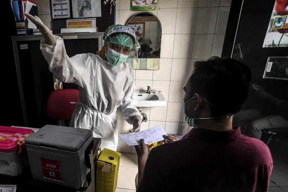 Petugas kesehatan memberikan penjelasan kepada seorang pasien usai divaksin saat simulasi pemberian vaksin COVID-19 Sinovac di Puskesmas Kelurahan Cilincing I, Jakarta, Selasa (12/1/2021). Simulasi tersebut digelar sebagai persiapan penyuntikan vaksinasi 