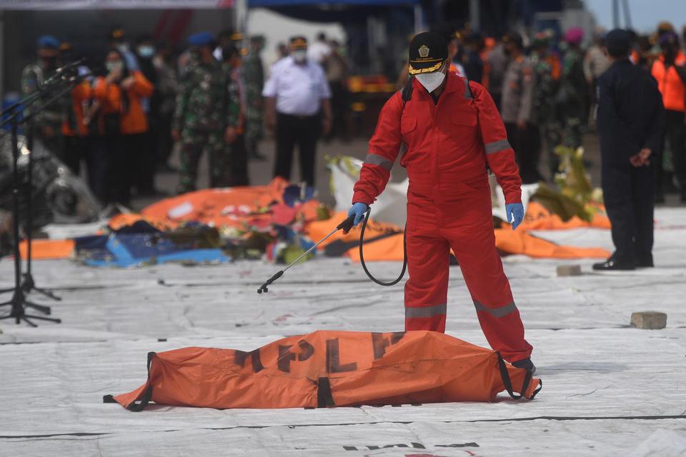 Petugas menyemprotkan disinfektan ke kantung jenazah korban pesawat Sriwijaya Air PK-CLC nomor penerbangan SJ-182 yang jatuh di perairan Pulau Seribu, di Dermaga JICT, Jakarta, Selasa (12/1/2021).