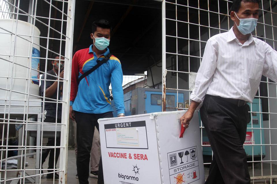 Petugas mengangkat dus berisi vaksin COVID-19 yang akan didistribusikan di Dinas Kesehatan Provinsi Sumatera Barat, Padang, Rabu (13/1/2021). Dinas Kesehatan Provinsi Sumatera Barat mulai mendistribusikan vaksin COVID-19 Sinovac ke dua daerah penerima vak