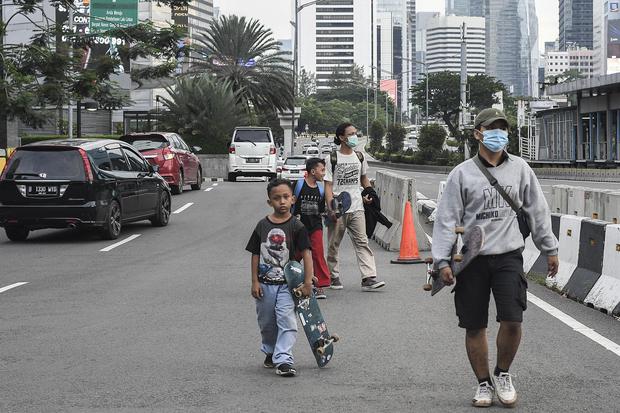 Dua orang warga tidak menggunakan masker saat melintas di daerah Sudirman, Jakarta, Sabtu (16/1/2021). Berdasarkan data Satuan Tugas Penanganan COVID-19 pada Sabtu (16/1) kasus positif COVID-19 bertambah 14.224 orang menjadi 896.642 orang, sementara kasus