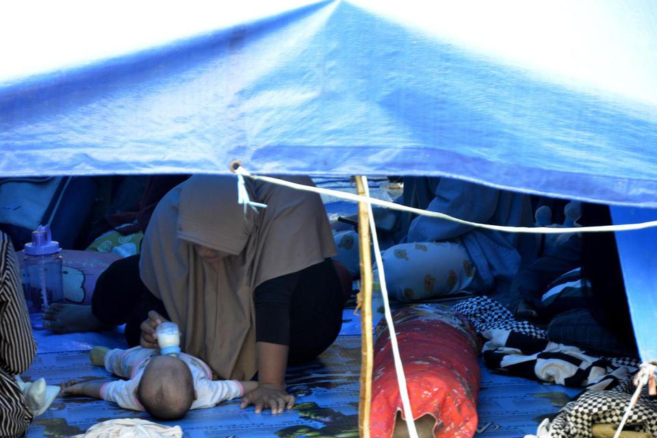 Warga korban gempa bumi mengungsi di halaman Rumah Sakit Umum Kabupaten Mamuju di Sulawesi Barat, Minggu (17/1/2021). Sebanyak 27.850 jiwa telah mengungsi di sejumlah posko pengungsian karena rumah mereka rusak akibat gempa bumi berkekuatan magnitudo 6,2 