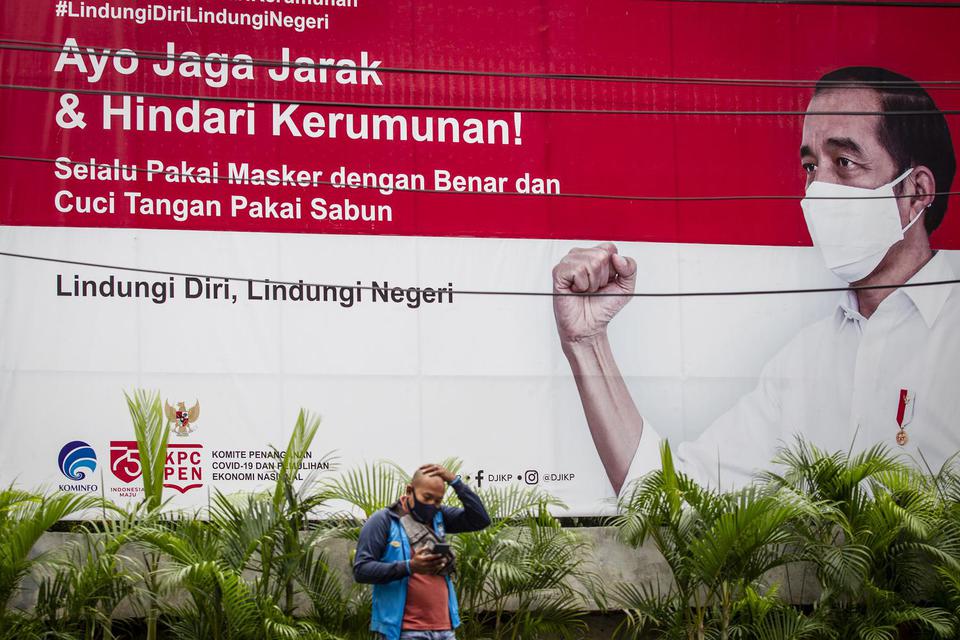 Warga beraktivitas di depan baliho informasi tentang pandemi COVID-19 di Jakarta, Selasa (19/1/2021). Hingga Selasa (19/1) pukul 16.00 WIB kasus terkonfirmasi COVID-19 di Indonesia mencapai 927.380 kasus dengan total pasien sembuh sebanyak 753.948 orang d