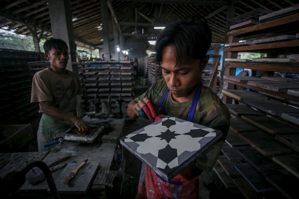 Pekerja menyelesaikan pembuatan keramik lantai bermotif di Keniten, Tamanmartani, Kalasan, Sleman, DI Yogyakarta.