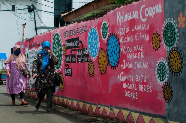 Warga melintasi mural edukasi pencegahan COVID-19 berbahasa Sunda di Pandeglang, Banten, Selasa (26/1/2021). Mural tersebut bertujuan sebagai media edukasi untuk mengingatkan warga agar menerapkan protokol kesehatan 3M (memakai masker, mencuci tangan, dan