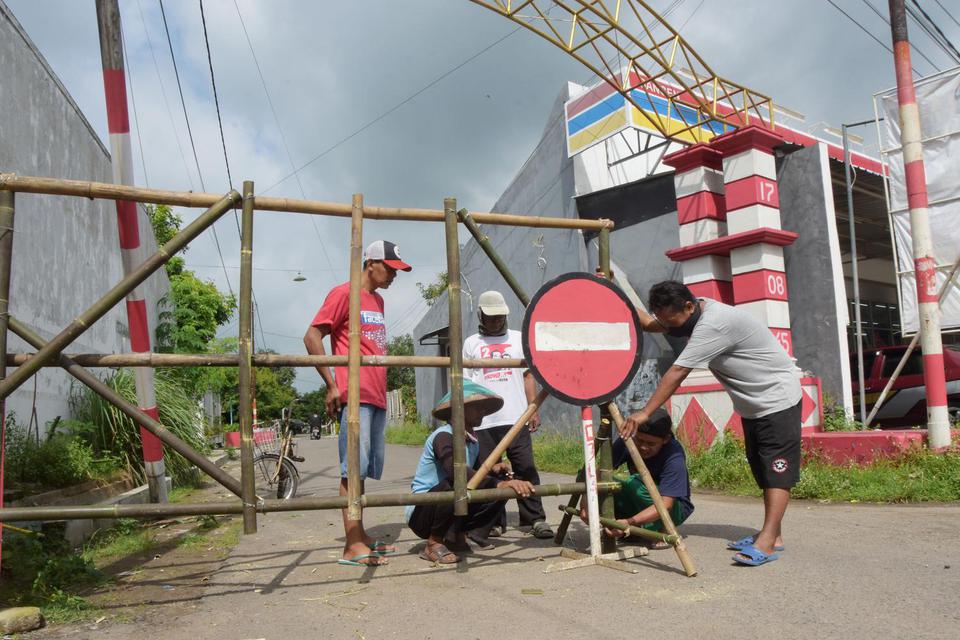 Warga membuat portal penutup jalan di Desa Sangen, Kecamatan Geger, Kabupaten Madiun, Jawa Timur, Selasa (2/2/2021). Pemkab Madiun bersama masyarakat menerapkan sistem satu pintu untuk akses keluar masuk wilayah di setiap desa pada masa perpanjangan Pembe