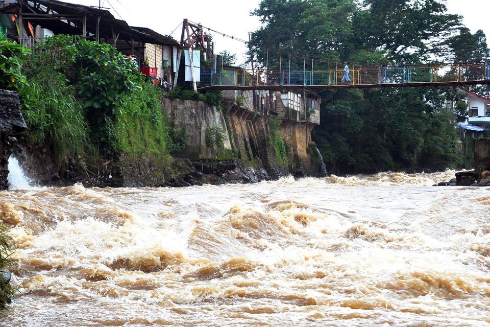 Warga berjalan di atas jembatan sungai Ciliwung yang arus airnya deras, di Kelurahan Sempur, Kota Bogor, Jawa Barat, Selasa (9/2/2021). BMKG merilis anomali iklim La Nina sedang berkembang di Samudera Pasifik, dampaknya pada Indonesia dapat menyebabkan cu
