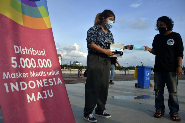Seorang warga menerima masker medis saat gerakan distribusi lima juta masker medis di Makassar, Sulawesi Selatan, Rabu (17/2/2021). Gerakan distribusi lima juta masker medis yang dilaksanakan GP Ansor dan Aice Group tersebut didistribusikan kepada masyara