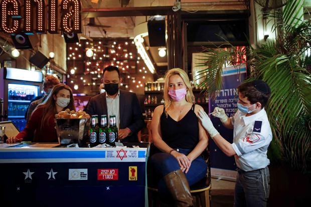 Corinna Kern Seorang wanita menerima vaksinasi melawan virus corona (COVID-19) sebagai bagian dari inisiatif kota Tel Aviv yang menawarkan minuman gratis di sebuah bar kepada penduduk yang mendapatkan suntikan, di Tel Aviv, Israel, Kamis (18/2/2021)